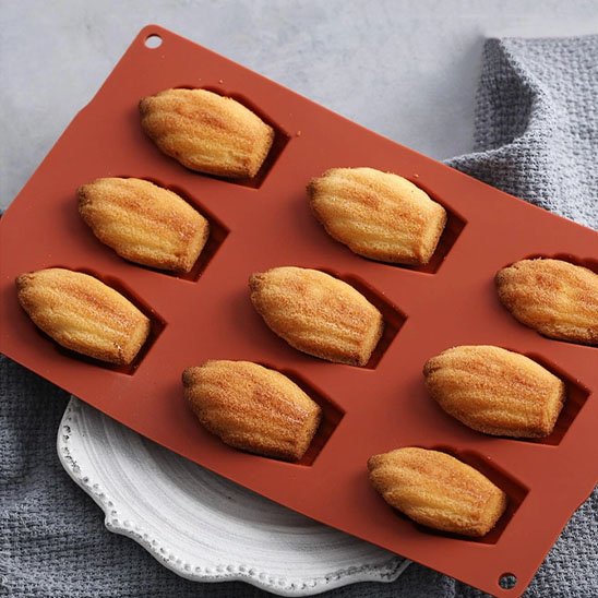 Moule à madeleine Premium Silicone couleur rouille avec 9 madeleines sur assiette blanche