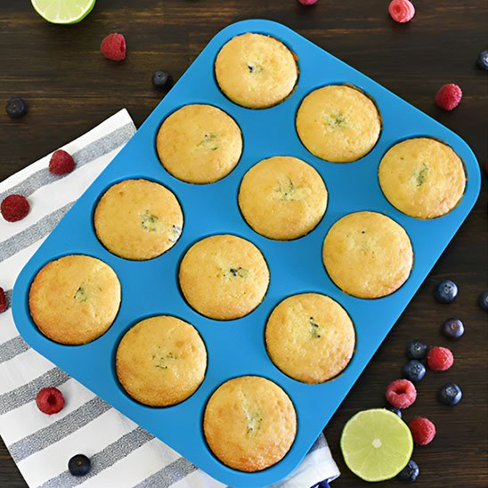 Moule à muffin EasyBake bleu avec 8 muffins cuits sur table brune et petits fruits