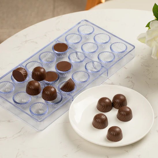 Moule à chocolat transparent avec chocolat dans une petite assiette blanche