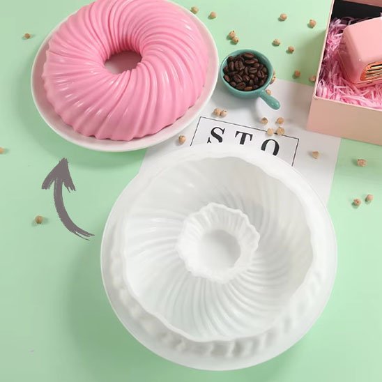 Moule à gâteau en silicone avec gâteau rose dans une assiège blanche sur fond vert

