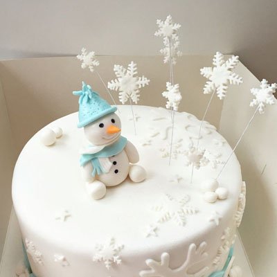 Emporte pièces Noël Festivo dans un gateau blanc avec figurine de bonhomme de neige
