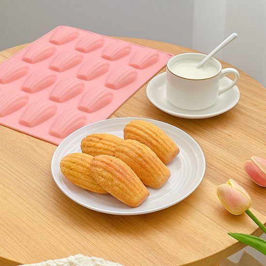 Moule à madeleine FlexiBake rose avec 5 madeleines dans assiette blanche et tasse à café