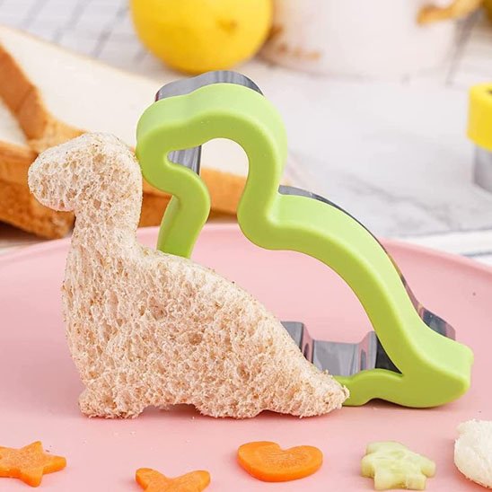 Emporte pièce en forme de dinosaure de couleur vert découpé dans un sandwich
