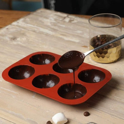 Moule à gâteau en silicone a moitié rempli avec du chocolat avec une cuillère