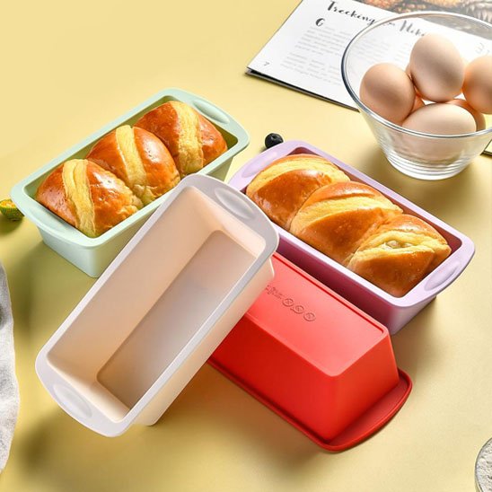 4 Moule à gâteau silicone PâtissiPro de couleurs variés avec deux gâteaux cuits et bol contenant des oeufs