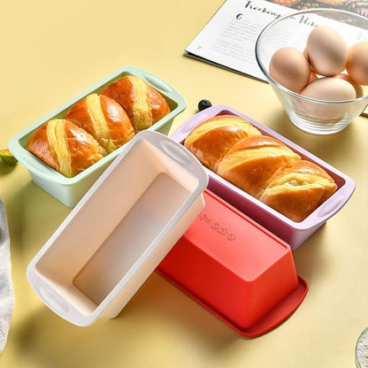 4 Moule à gâteau silicone PâtissiPro de couleurs variés avec deux gâteaux cuits et bol contenant des oeufs