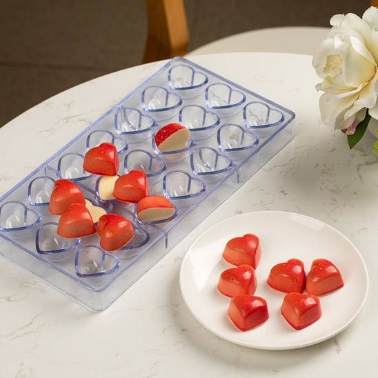 Moule à chocolat transparent avec chocolat en cœur rouge dans une assiette blanche