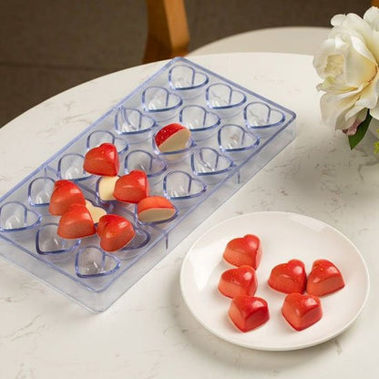 Moule à chocolat transparent avec chocolat en cœur rouge dans une assiette blanche