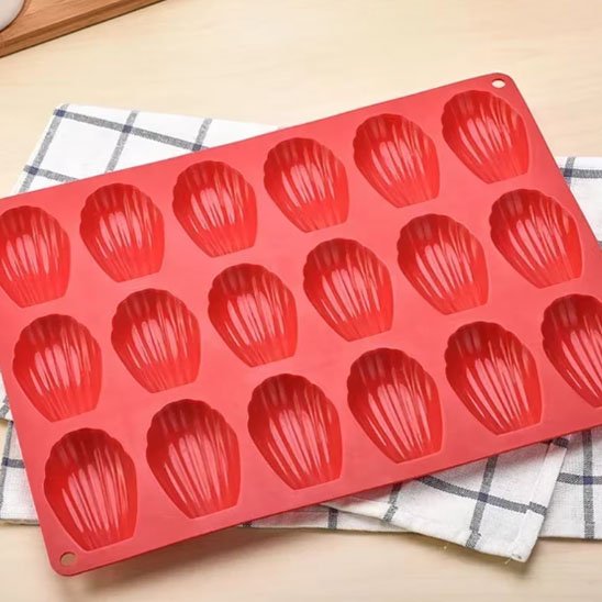 Moule à madeleine Premium Silicone de couleur rouge sur nappe carotté grise et blanche