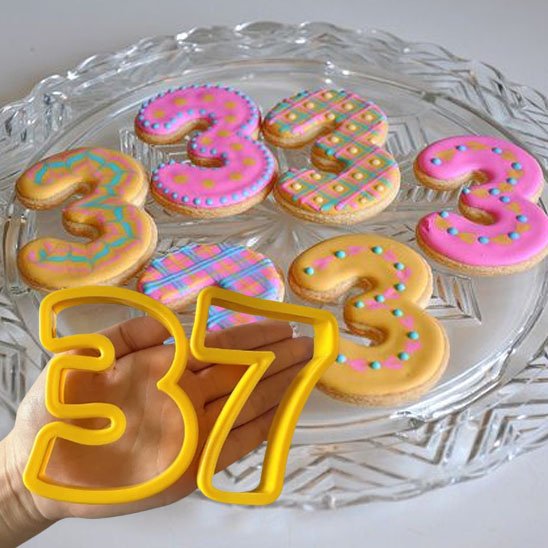 Moule number cake de couleur jaune avec le chiffre 3 et  dans la main avec 6 biscuits portant le chiffre 3