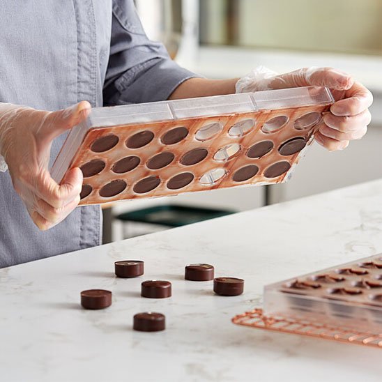 Moule à chocolat transparent  avec chocolat sur comptoir blanc